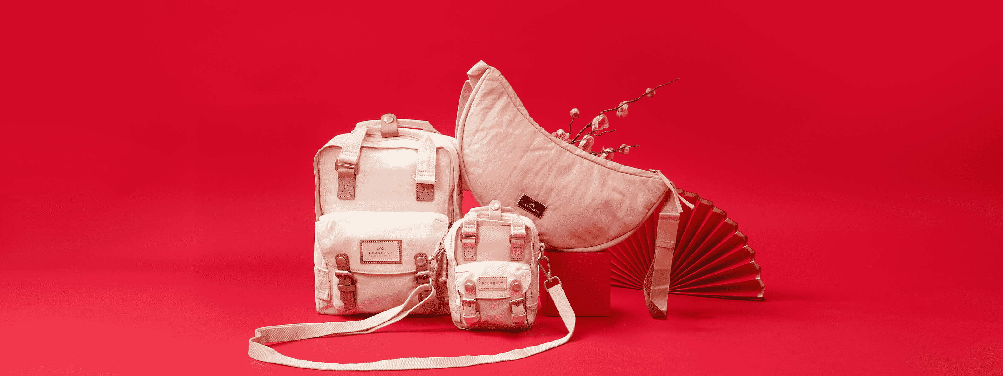 Dubai, UAE, Shopiva Doughnut pastel pink backpacks and crossbody bag displayed on a red background.